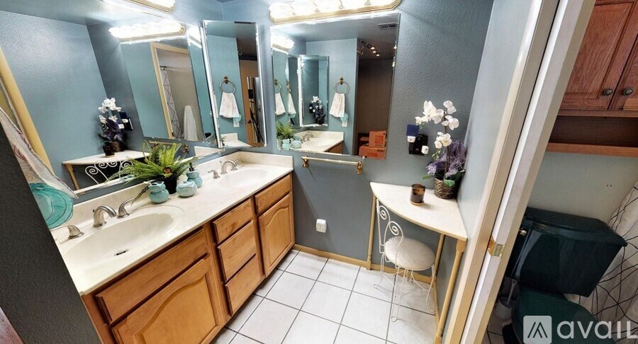 A bathroom with a sink, mirror, and a small table with a chair.