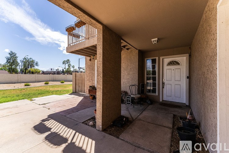 A balcony with a chair and a table is on the second floor of a house.