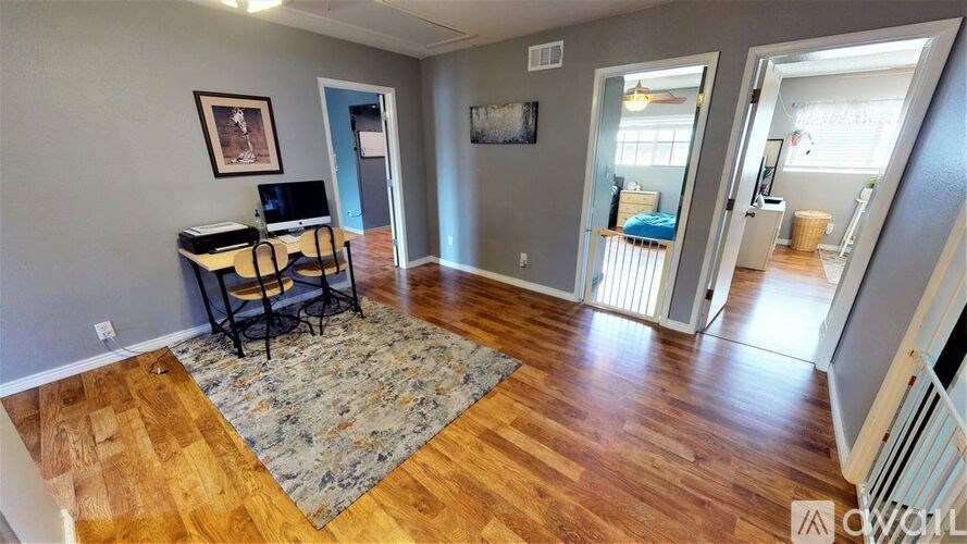 A room with wood flooring and a desk with a computer.