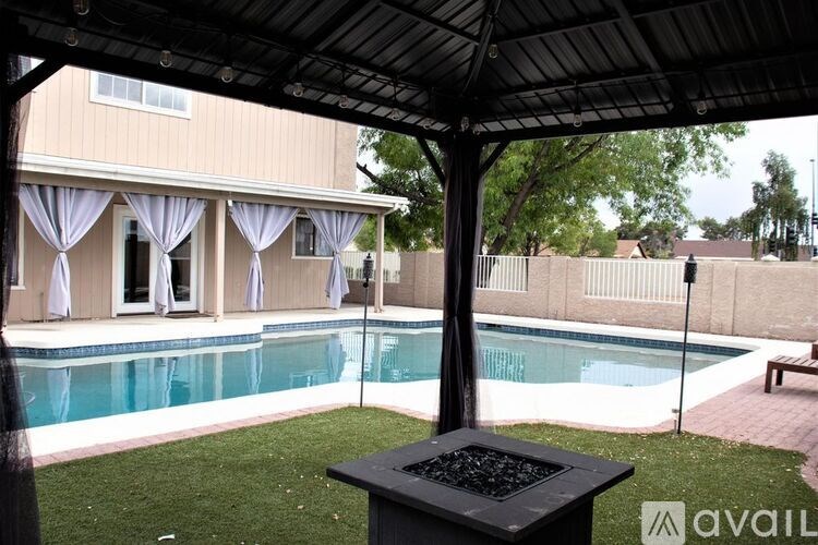 A pool area with a grill and a house in the background.