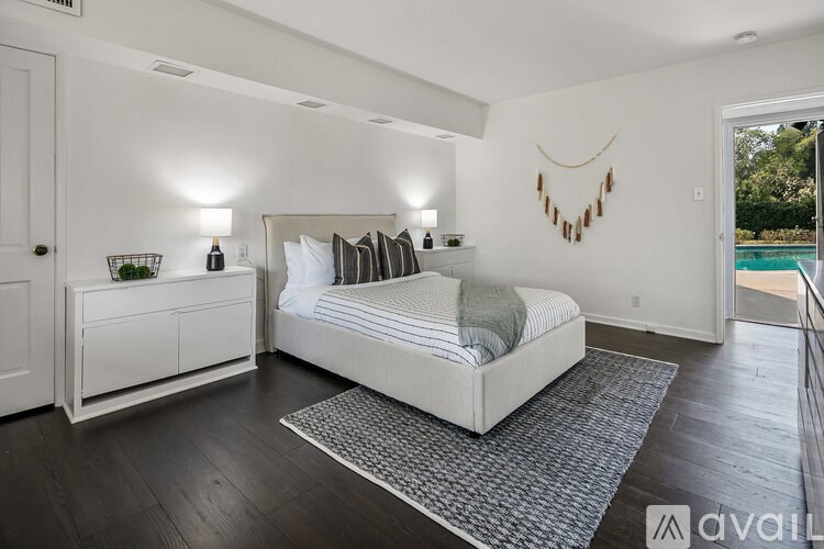 A bedroom with a large bed and a white dresser.