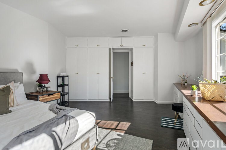 A bedroom with a bed, nightstand, and a window with a view of a building outside.