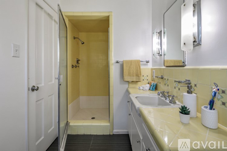 A bathroom with a sink, mirror, and shower.