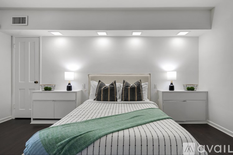 A bedroom with a bed, nightstands, and a green throw blanket.