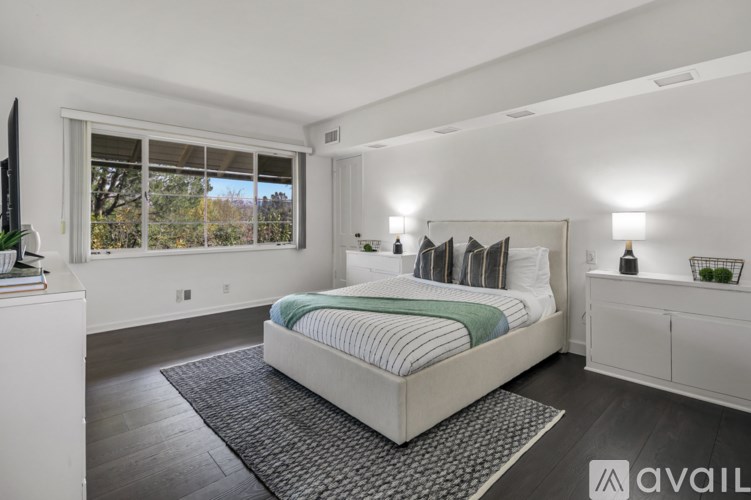 A bedroom with a large bed, a window, and a white cabinet.