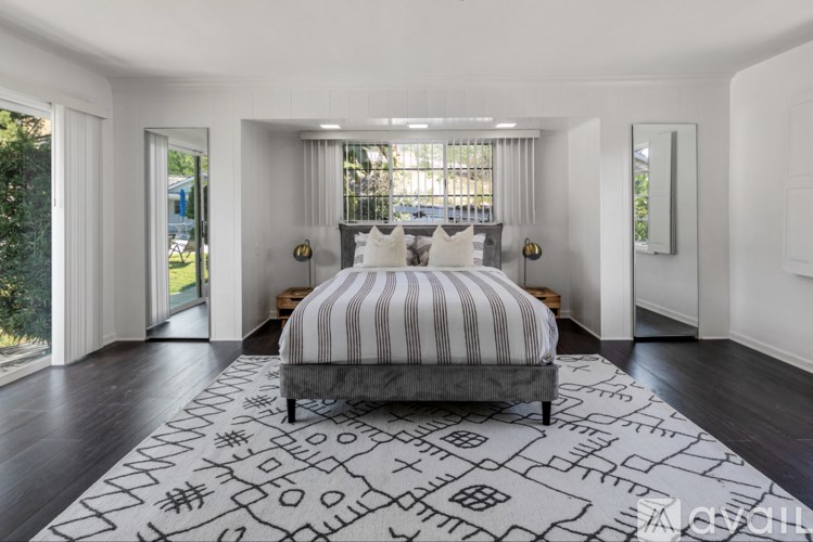 A bedroom with a large bed and a patterned rug.