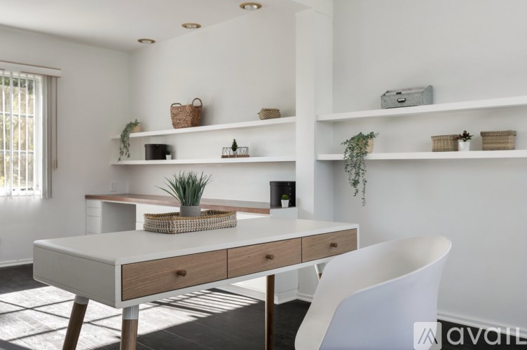 A white desk with a plant on it and a white chair in front of it.