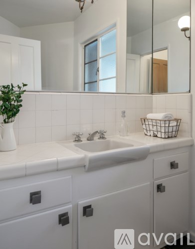 A white bathroom with a sink and a mirror.