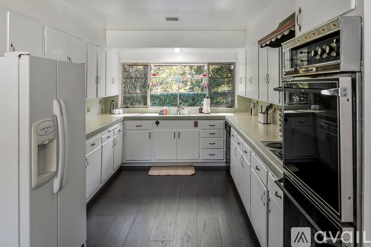 A kitchen with white cabinets and appliances is available for rent.