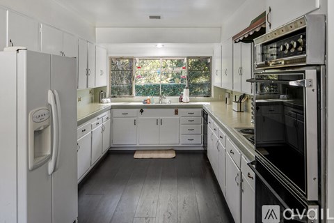 A kitchen with white cabinets and appliances is available for rent.