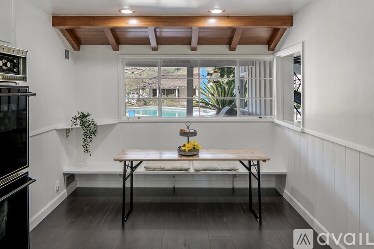 A dining room with a table and chairs and a plant on the table.