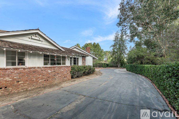 A house with a driveway and a hedge on the side.