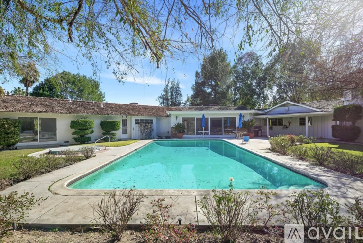 A swimming pool in a backyard with a house in the background.