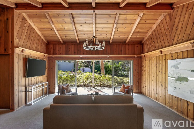 A living room with wooden walls and ceiling, a couch, and a television.