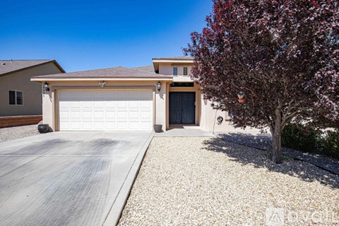 A house with a white garage door and a tree in front.