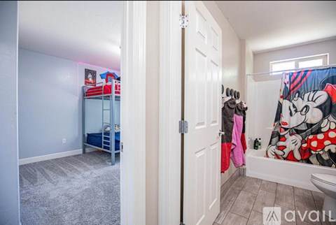 A bedroom with a bunk bed and a bathroom with a shower curtain featuring a cartoon character.