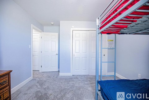 A bedroom with a bunk bed and two white doors.