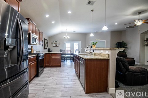 A kitchen with a refrigerator on the left and a counter with a plant on it.