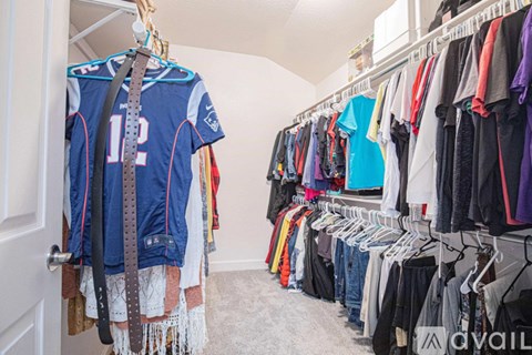 A room with a white door and a wall with clothes hanging on it.