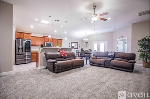 A living room with a brown couch and a ceiling fan.