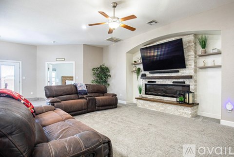 A living room with a brown leather couch and a flat screen TV mounted above a fireplace.
