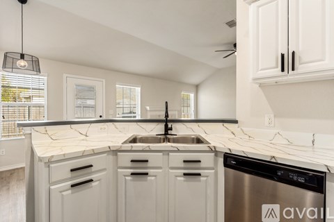 A kitchen with white cabinets and a marble countertop.