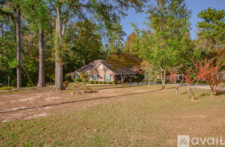A house surrounded by trees in a grassy area.