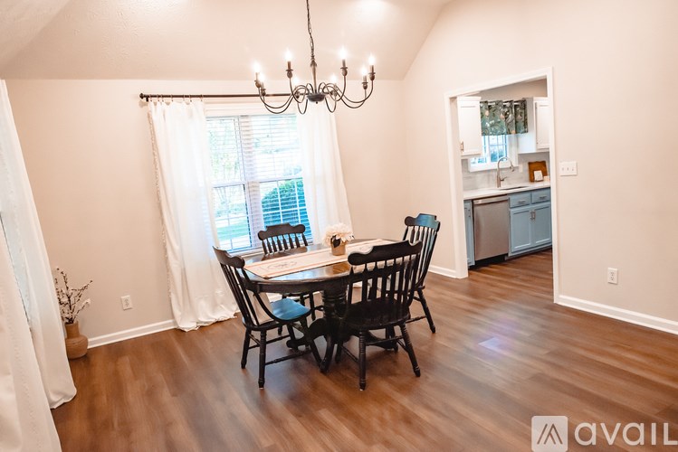 A dining room with a table set for four and a chandelier hanging from the ceiling.