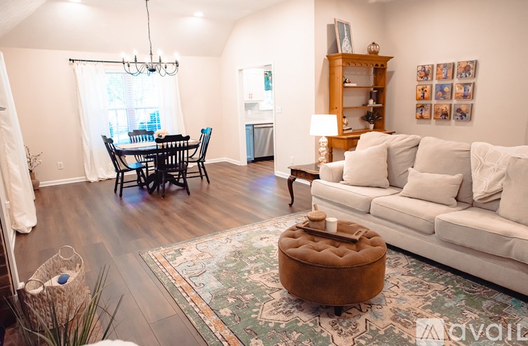 A living room with a white couch, a wooden coffee table, and a dining table with chairs.
