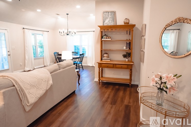 A well-lit living room with a white sofa and a wooden shelf.