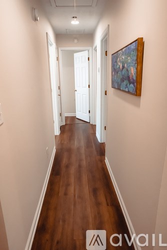 A hallway with wood floors and white walls.