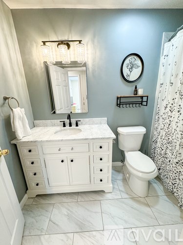A white bathroom with a marble counter top and a white toilet.