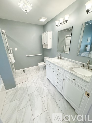 A bathroom with a marble floor and white cabinetry.