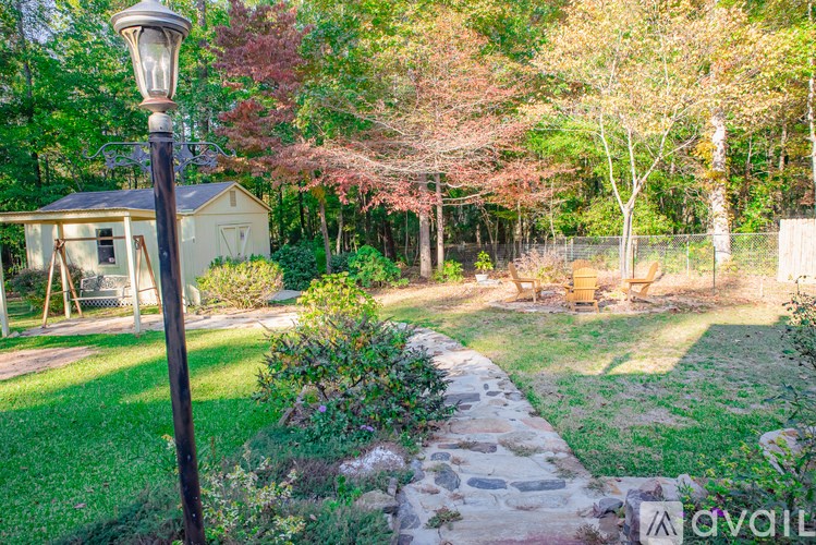 A garden with a lamp post and a house in the background.
