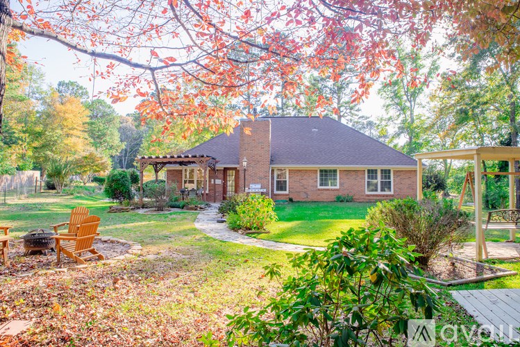A house with a red roof and a porch surrounded by trees with orange leaves.