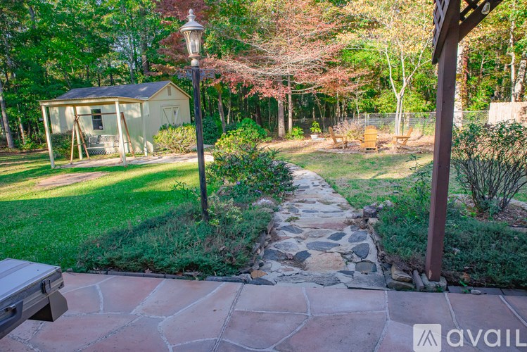 A stone pathway leads to a small house in a backyard.