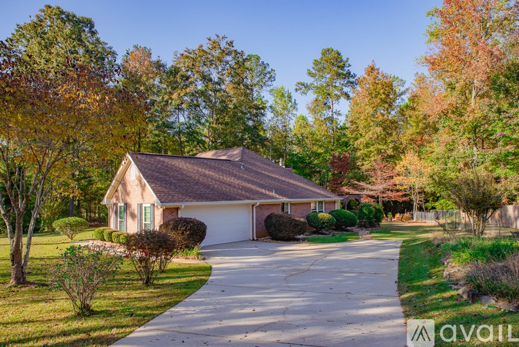 A house with a driveway and trees in the background.