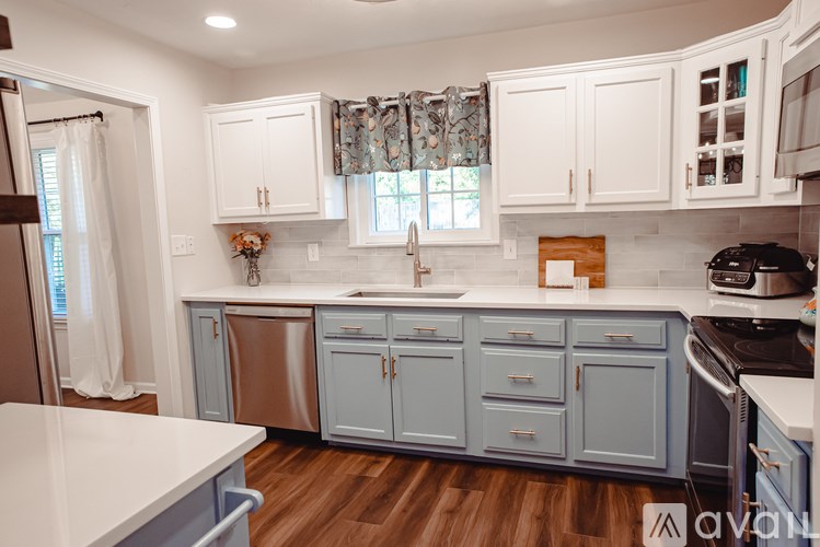 A kitchen with white cabinets and a wooden floor.