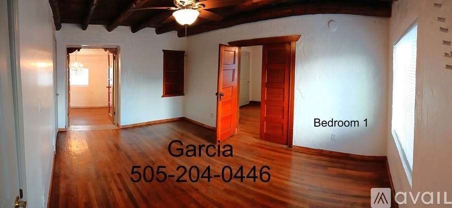A large empty room with wood floors and a ceiling fan.