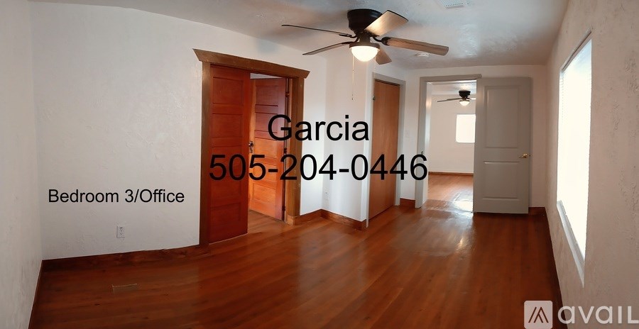 A room with a ceiling fan and a door leading to another room.