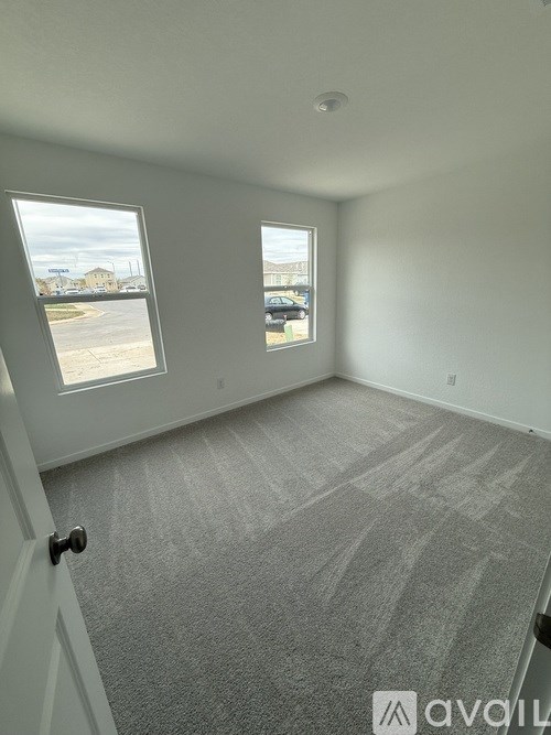 A room with a carpeted floor and two windows.