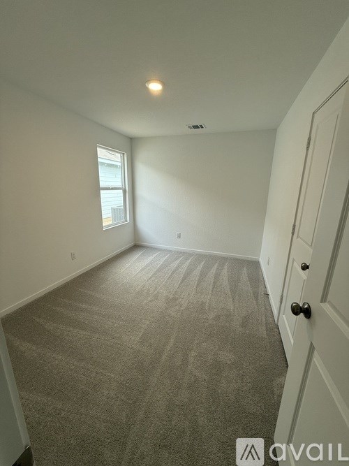 A room with a carpeted floor and a door on the right side.