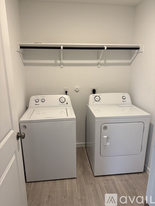 A small laundry room with two washers and a shelf above them.