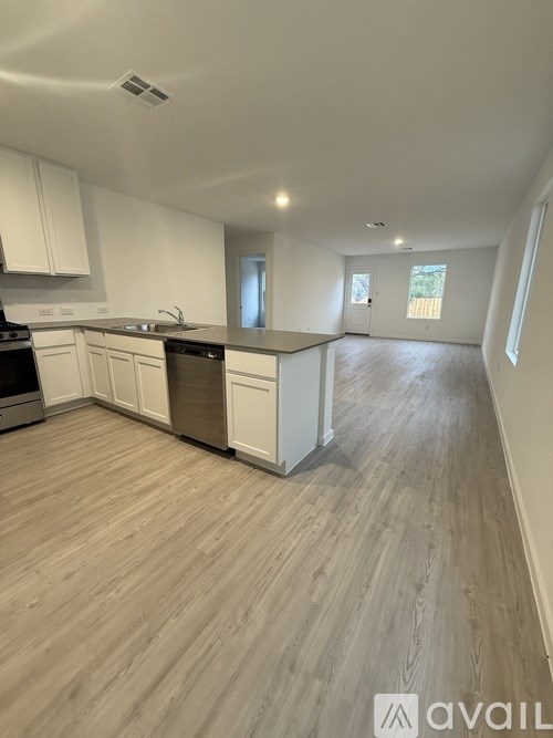 A kitchen with white cabinets and a wooden floor.