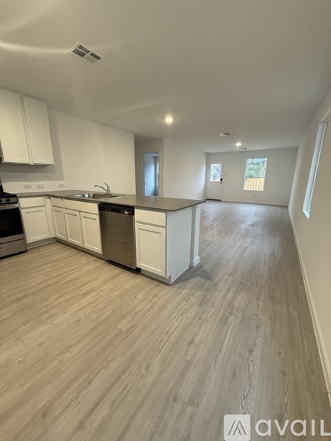 A kitchen with white cabinets and a wooden floor.