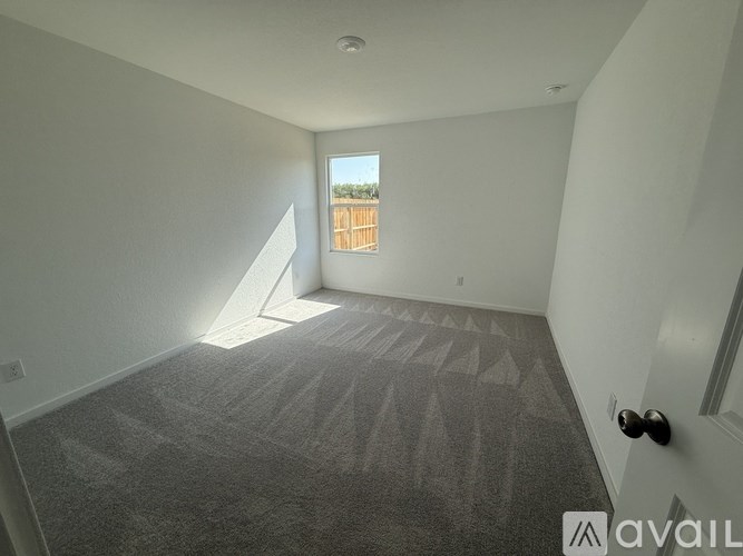 A room with a carpeted floor and a window overlooking a wooden fence.
