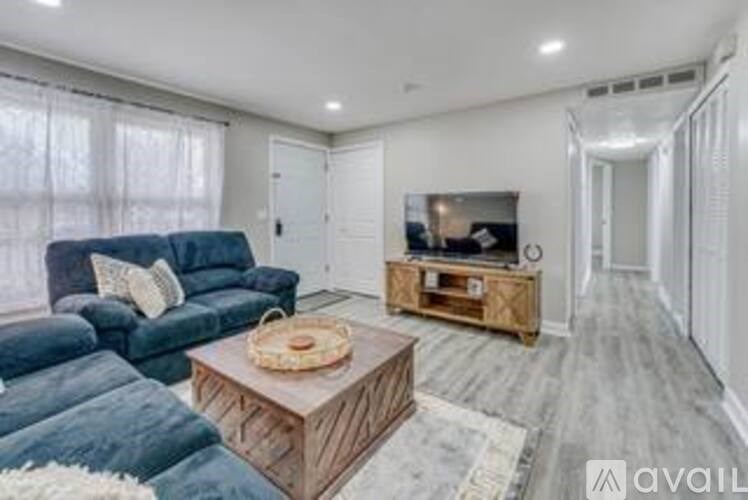 A living room with a blue couch, a wooden coffee table, and a television on a wooden stand.