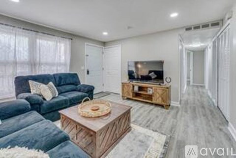 A living room with a blue couch, a wooden coffee table, and a television on a wooden stand.