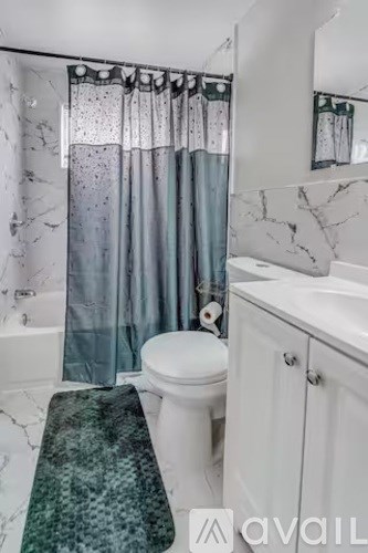 A bathroom with a toilet, sink, and shower curtain.