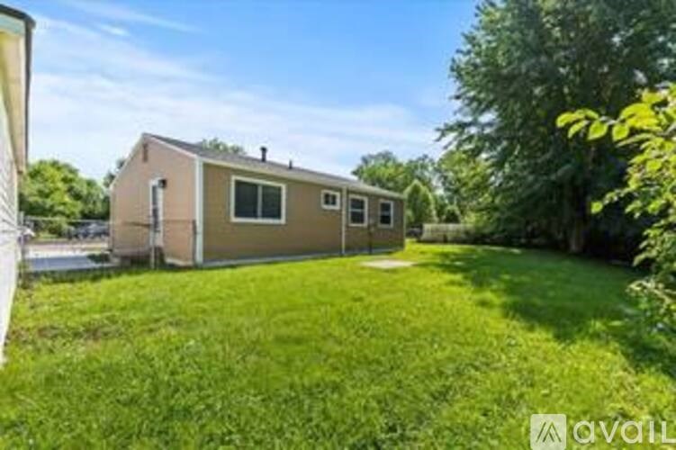 A mobile home sits in a grassy yard with trees in the background.
